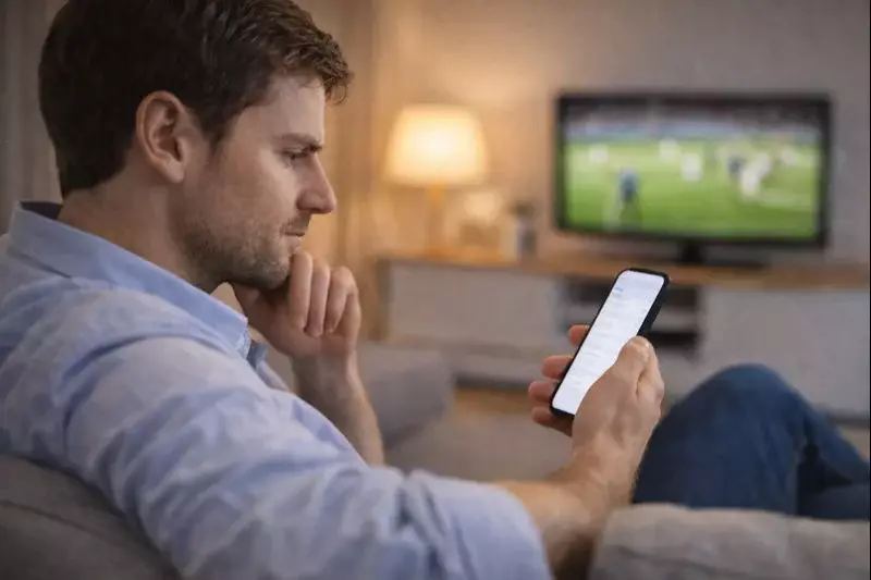 Uomo che utilizza smartphone per scommesse sportive dal divano